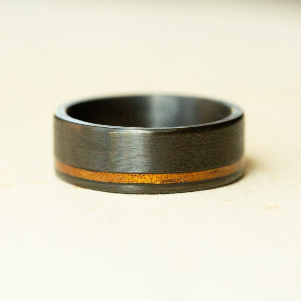 Black ring with a wooden inlay on a beige background
