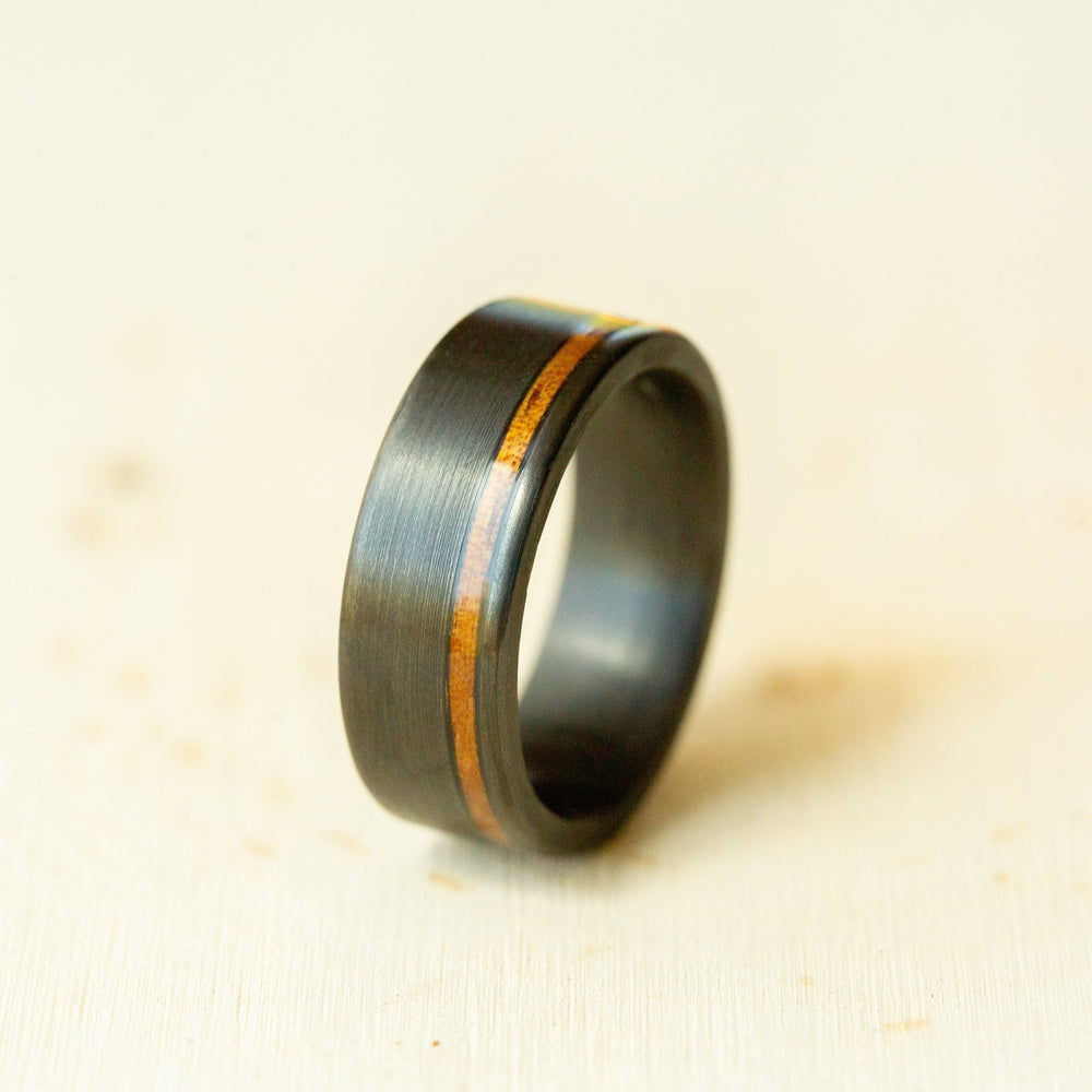 Black ring with a wooden inlay on a beige background