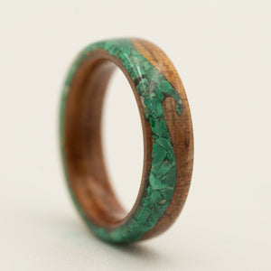 Wooden ring with green mineral inlay on a light background