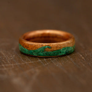 Wooden ring with green inlay on a wooden surface
