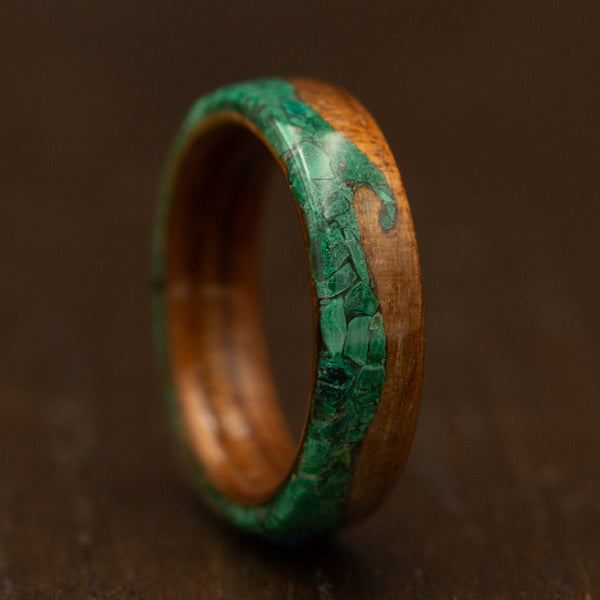Wooden ring with green inlay on a dark brown background