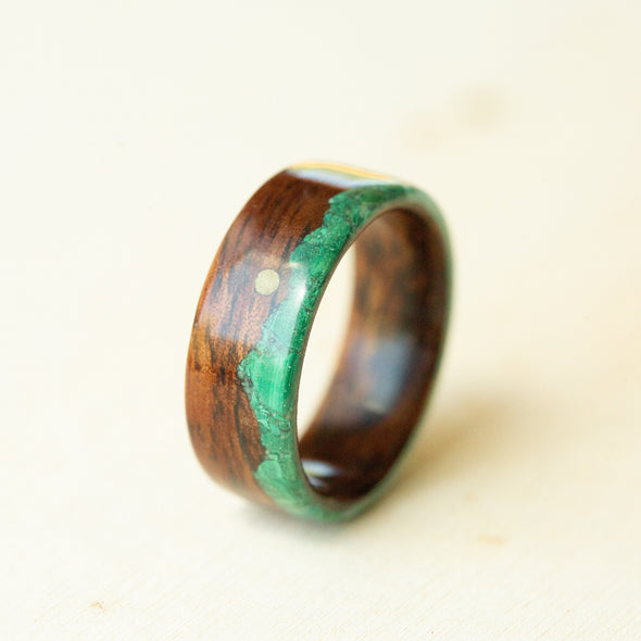 Wooden ring with green inlay on a light background