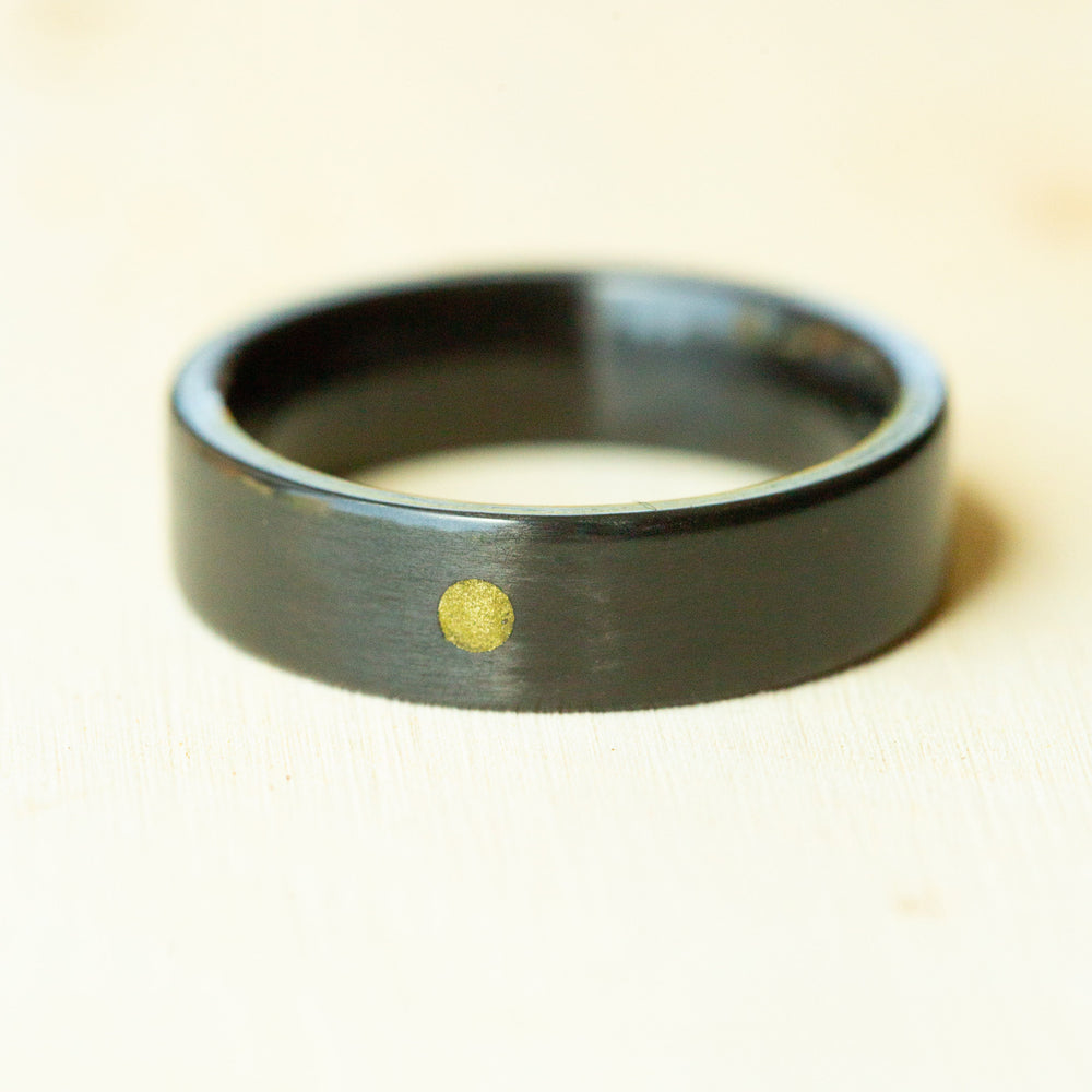 Black ring with a gold dot on a beige background