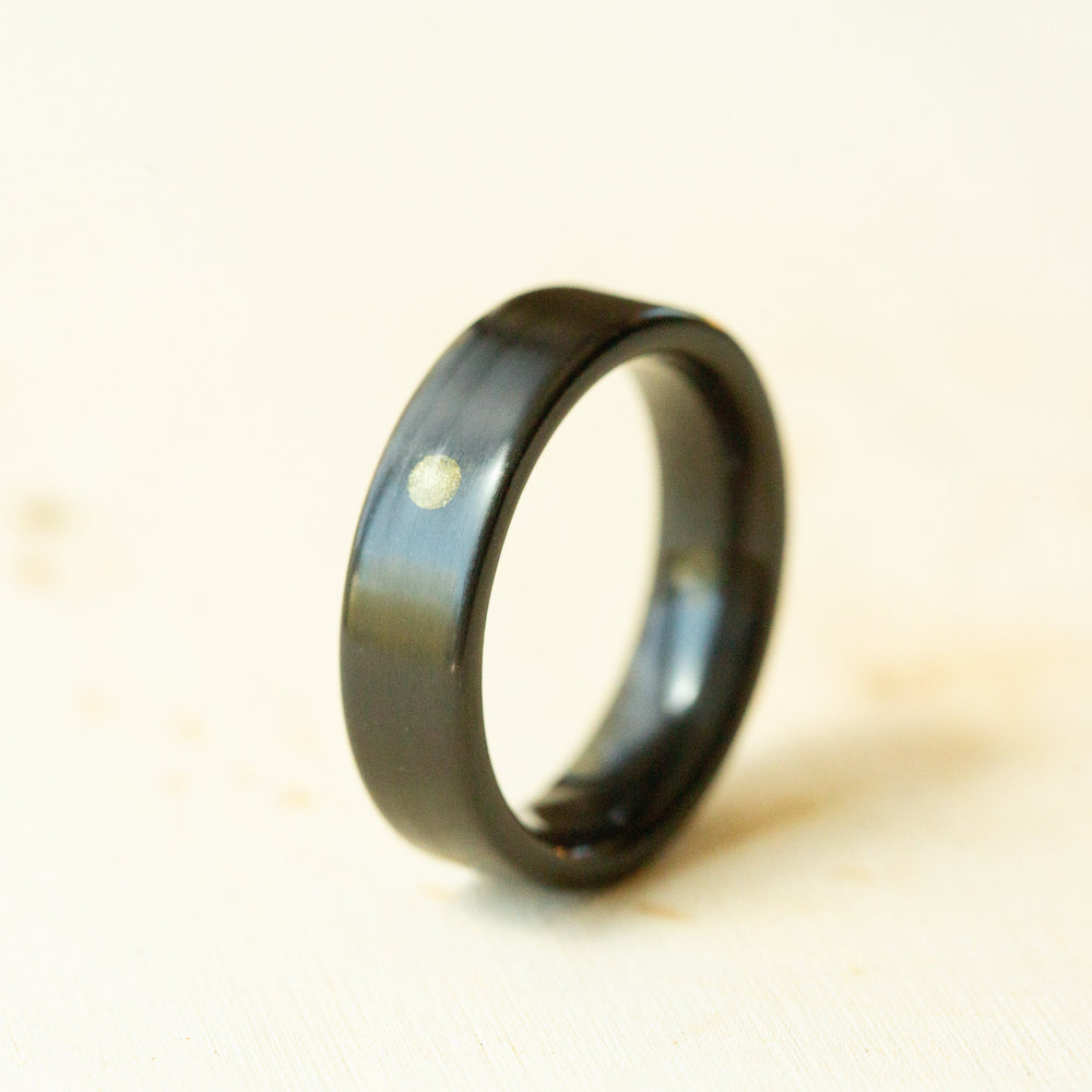 Black ring with a gold dot on a beige background