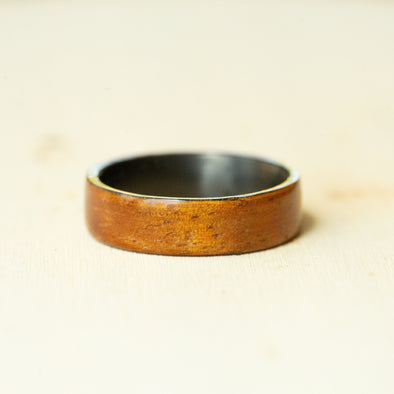 Wooden ring with a metallic band on a beige background