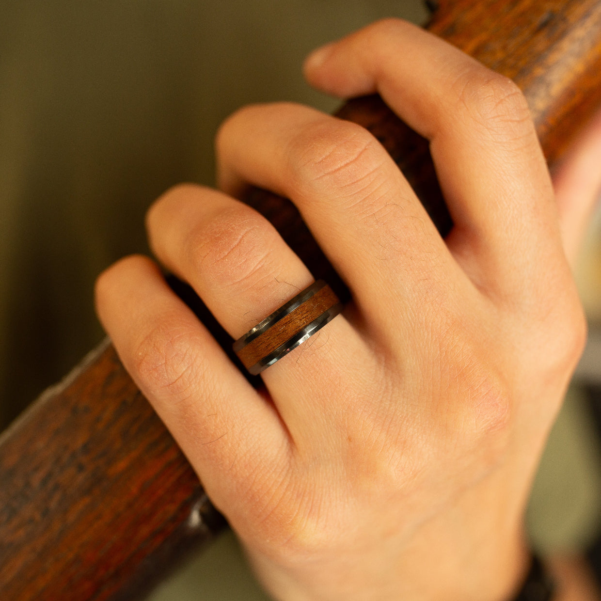 wood ring on hand holding a rifle