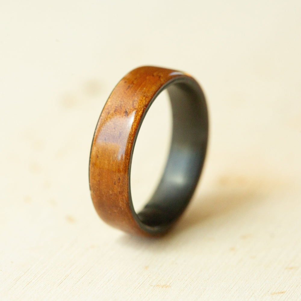 Wooden ring with a metallic band on a beige background
