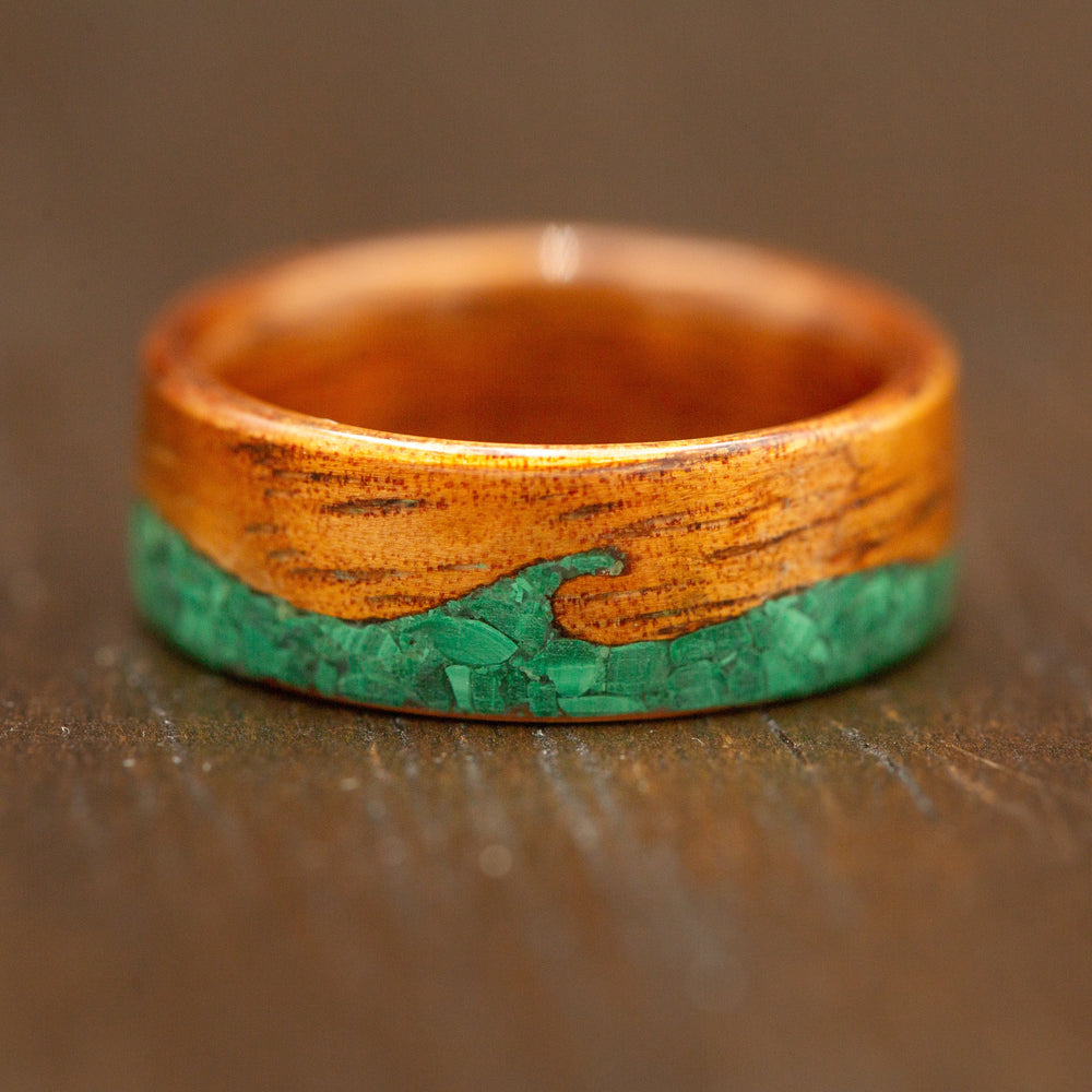 Wooden ring with a green inlay on a wooden surface