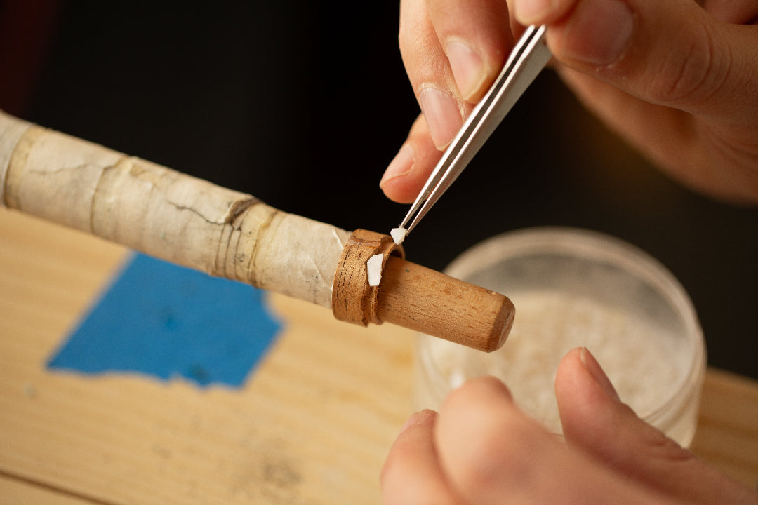 Person using a tool to work on a wooden object with a dark background