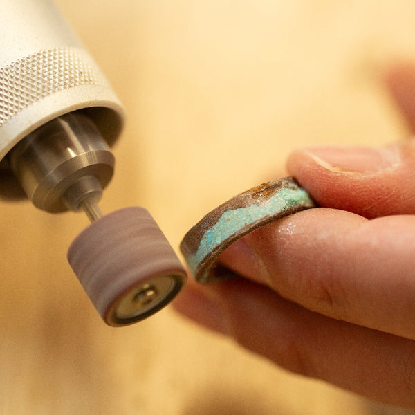 wood ring with turquoise mountain being sanded